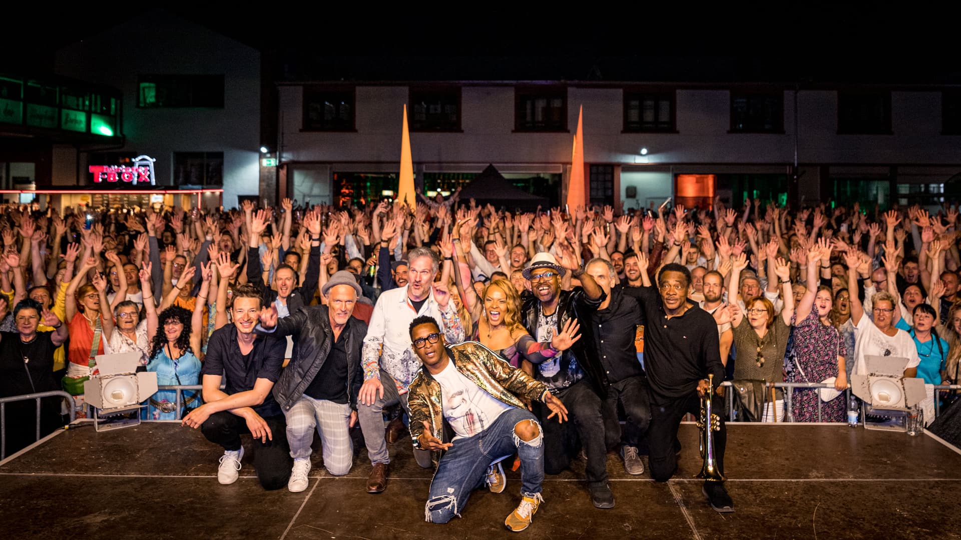 Band und riesiges Festival-Publikum, Gruppenfoto bei Nacht