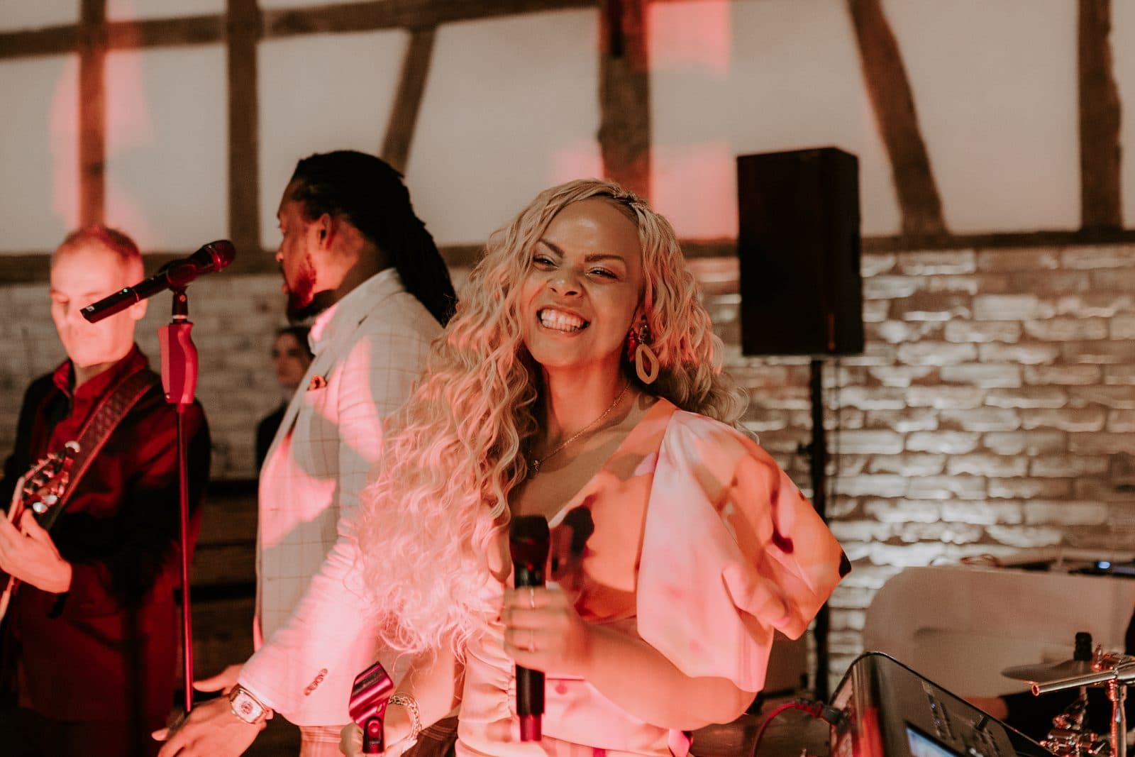 Amy Sue singt strahlend bei einer Hochzeit im Fachwerk-Setting mit Band