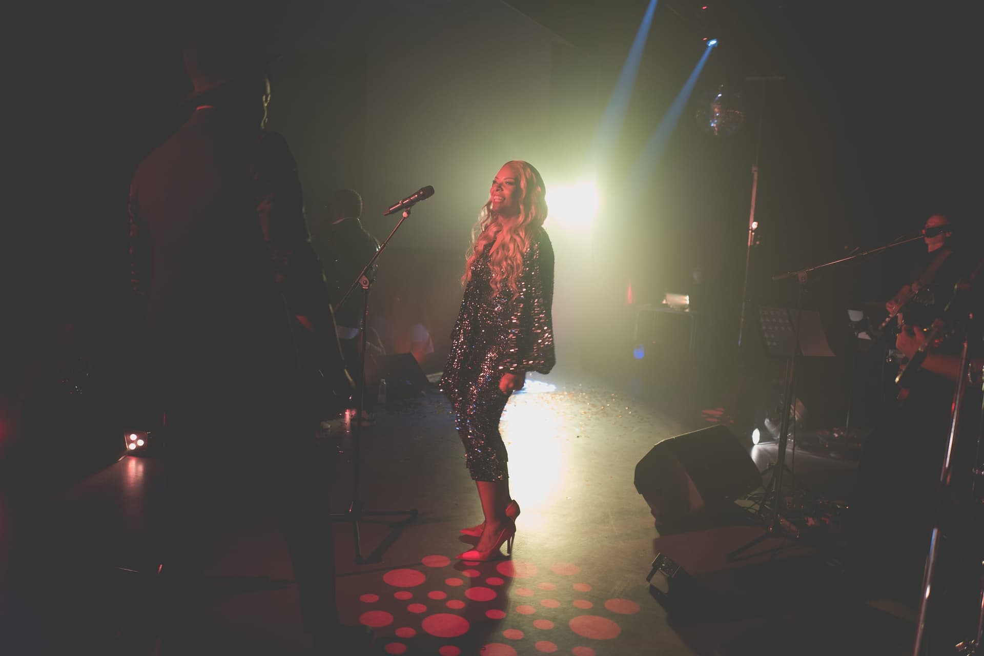 Amy Sue im Spotlight mit Band-Silhouetten und Discokugel