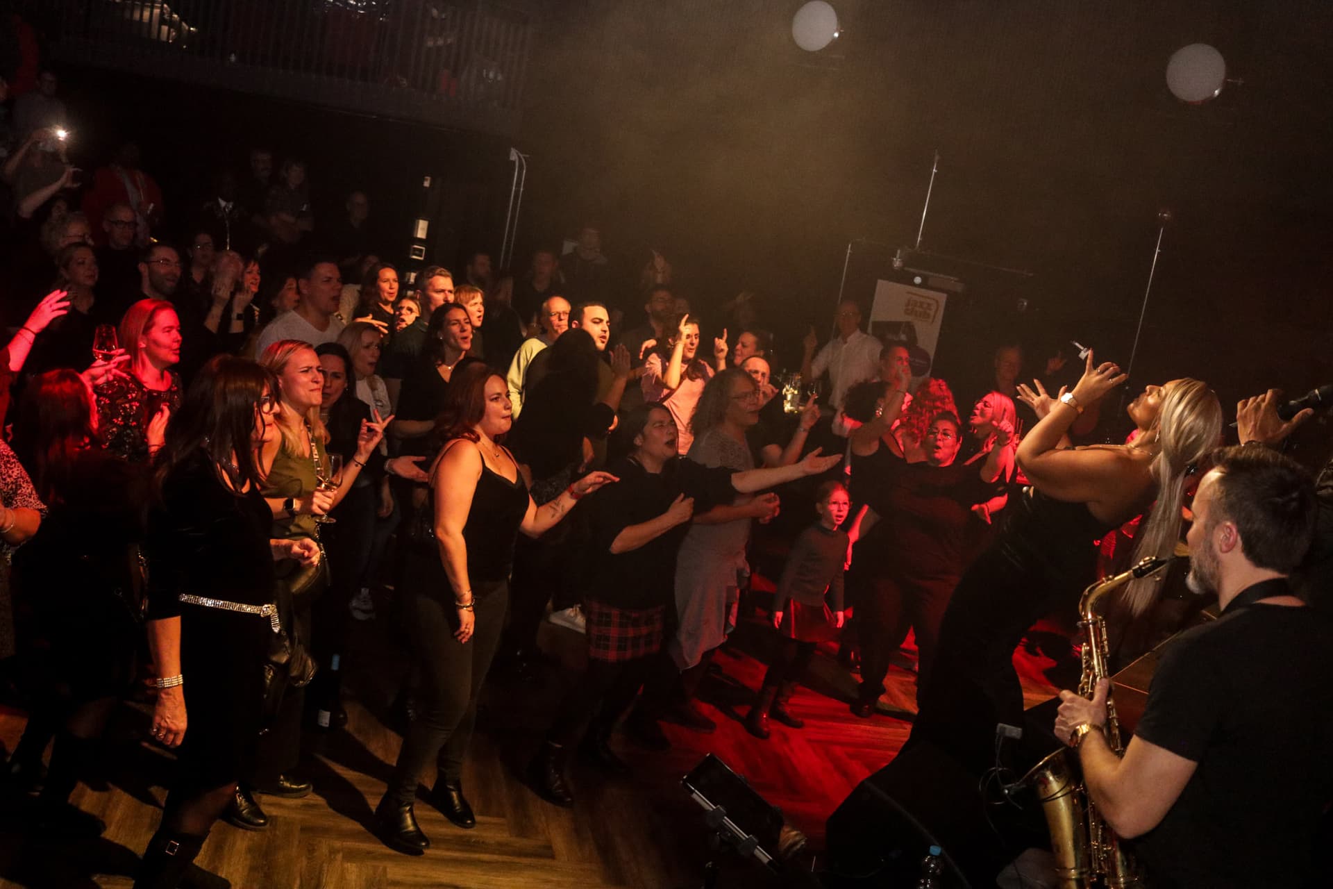 Begeistertes Publikum tanzt bei warmem goldenem Bühnenlicht