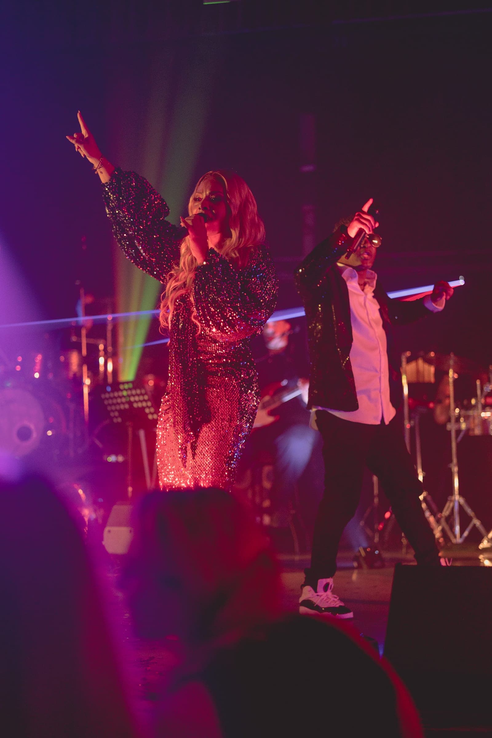 Amy Sue und Klyive im Sparkle-Outfit auf der Bühne, pink-lila Lichtshow mit Crowd