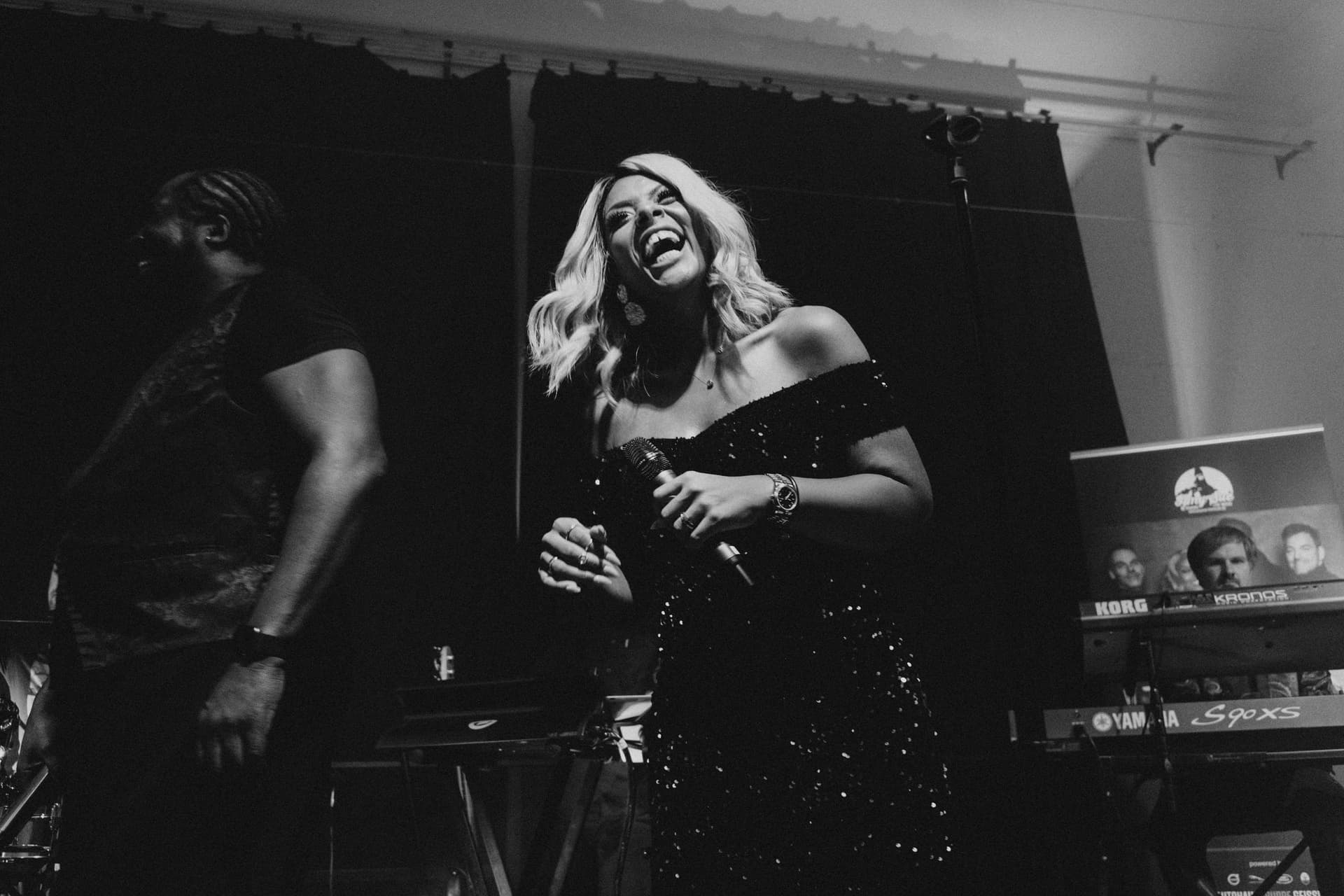 Amy Sue lachend mit Bandmitglied auf der Bühne, Schwarz-Weiß