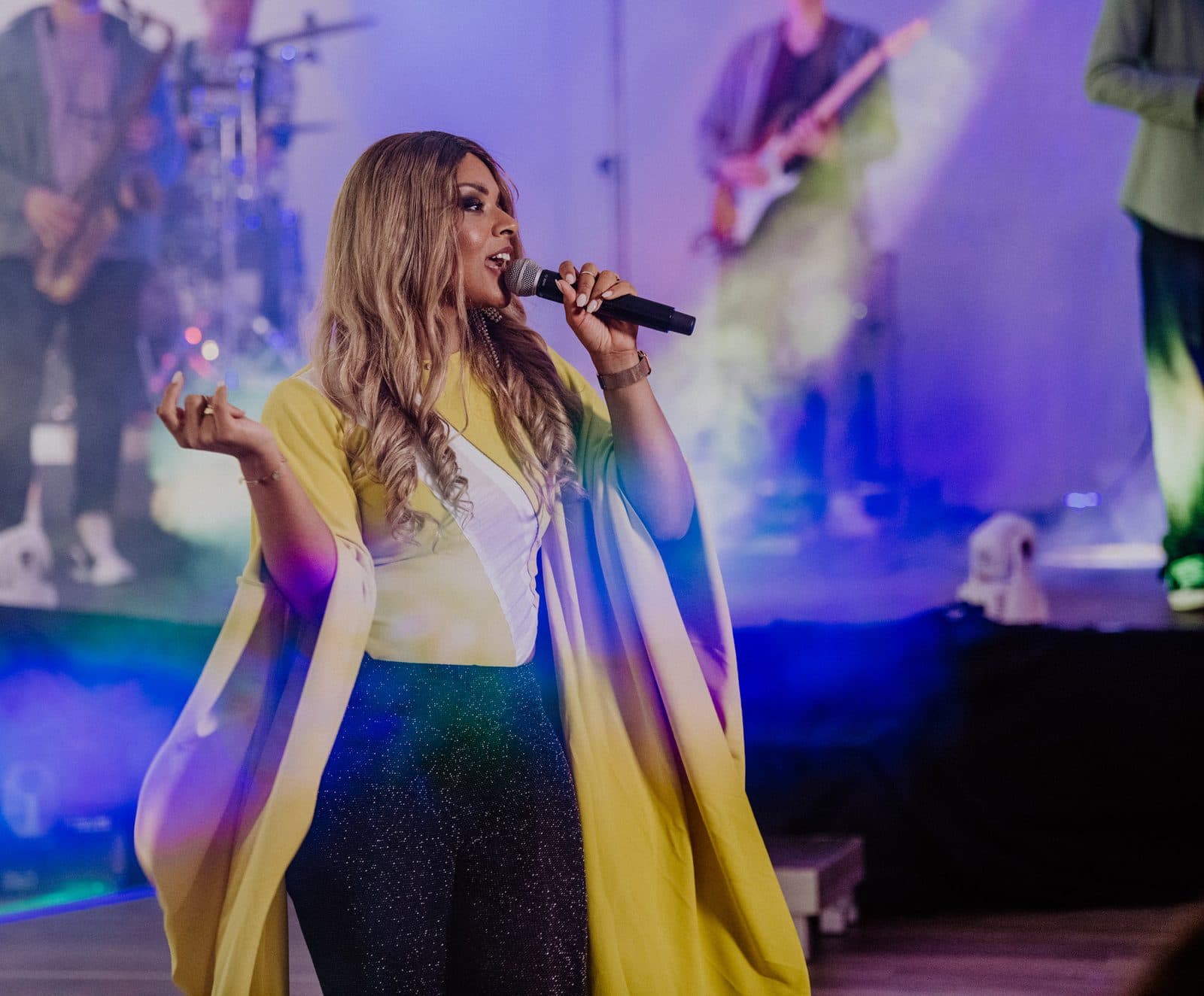 Amy Sue performt im gelben Outfit mit lila Bühnenbeleuchtung