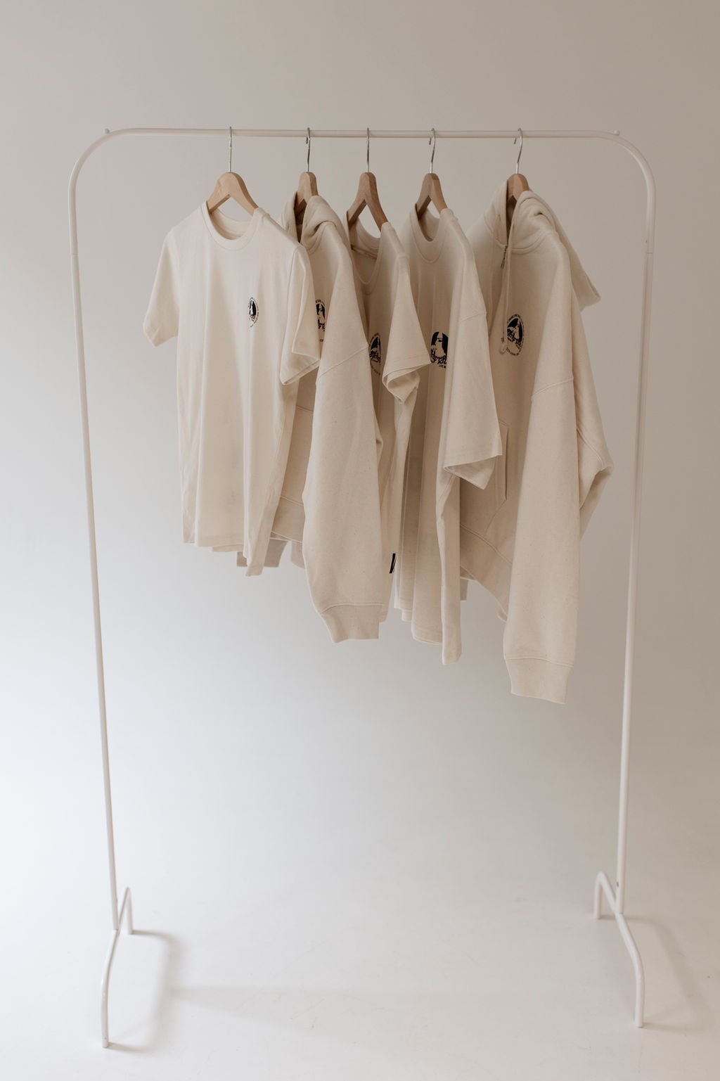 Die Jubiläums-Kollektion auf der Kleiderstange — das figurbetonte Damenshirt prominent links, mit dem schlankeren Rundhals-Schnitt neben den Oversize-Stücken