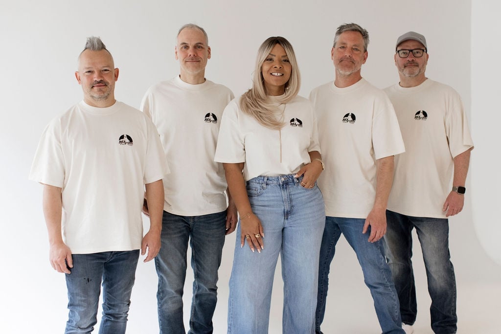 Amy Sue mit ihren vier Bandmitgliedern, alle vorne im T-Shirt mit dem Chest-Logo, entspannt in die Kamera lächelnd