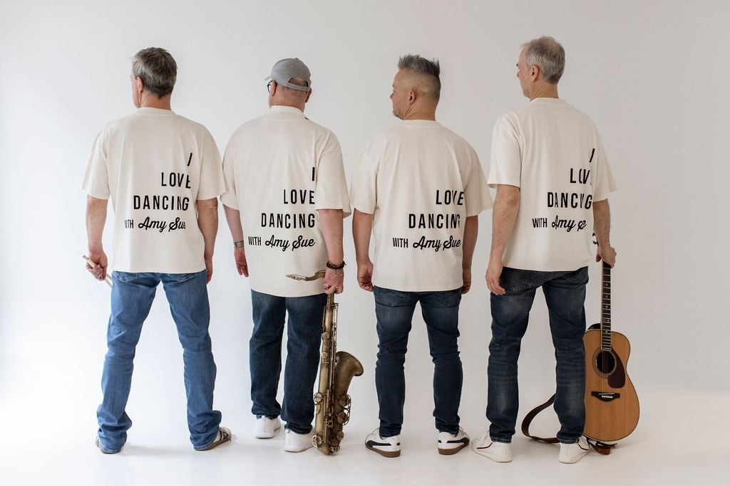 Vier Bandmitglieder von hinten im T-Shirt, der „I Love Dancing with Amy Sue"-Backprint in voller Typografie sichtbar